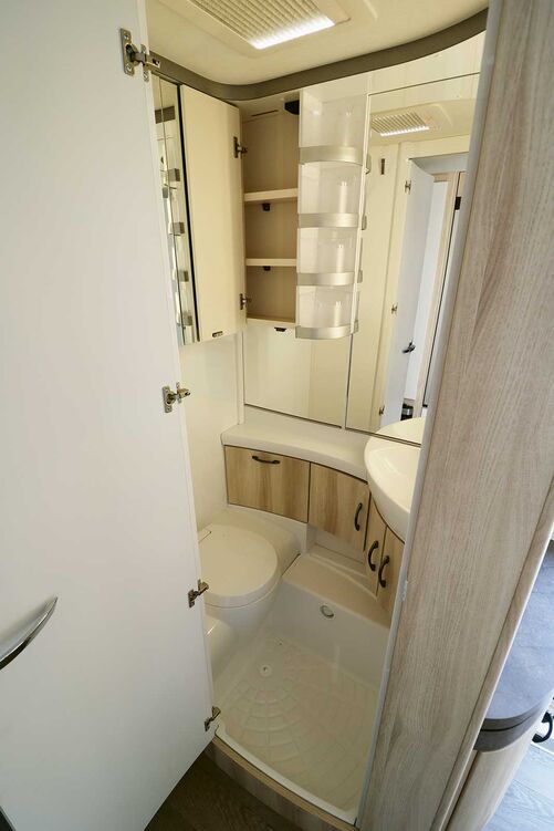 Lumineuse, la salle de bains avec élégant W.C. banc est mise en scène par de nombreux miroirs.