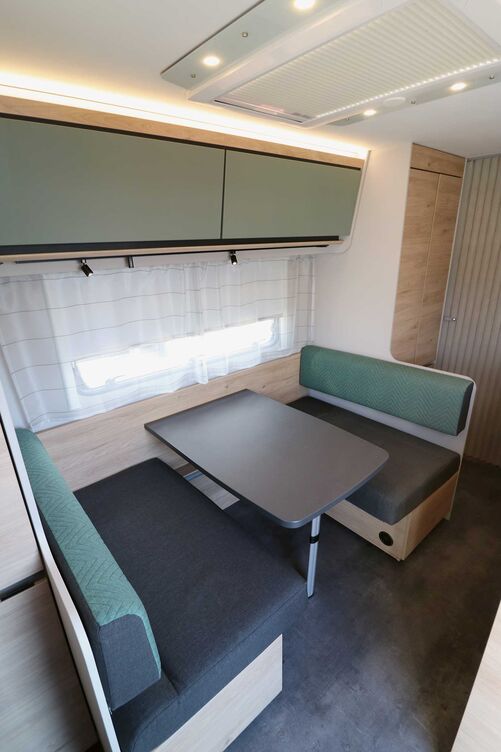 L’intérieur présente un style moderne et rectiligne, la combinaison entre les trappes d’armoires suspendues vert sauge, les surfaces beige, le décor bois chaud et les notes sombres créant un ensemble parfaitement harmonieux.