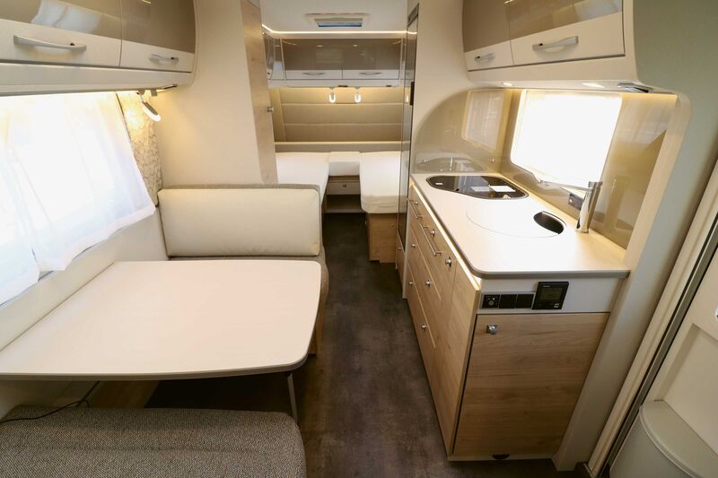La caravane Nomad présente une combinaison moderne d’éléments de mobilier clairs et d’inserts gris-beige brillants, qui créent une agréable sensation d’espace et une excellente ambiance intérieure en association avec la structure en bois à veines transversales.