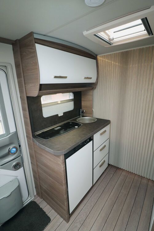 La cuisine compacte est élégante avec ses façades claires et offre un plan de travail suffisant grâce à la plaque de cuisson et à l’évier décalés vers l’arrière.