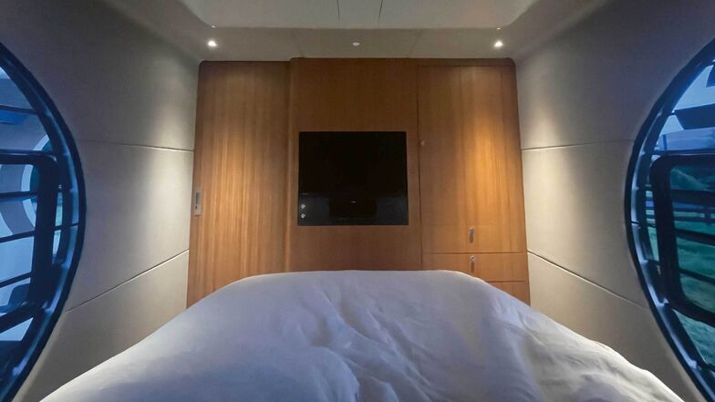 Porte de la chambre à gauche, téléviseur au milieu, penderie et tiroirs à droite.