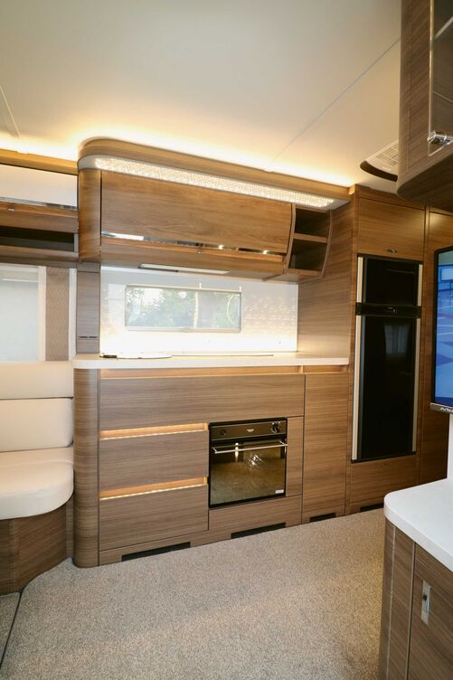 Élégante, la cuisine avec cadre de fenêtre éclairé présente des espaces de rangement et plans de travail suffisants.