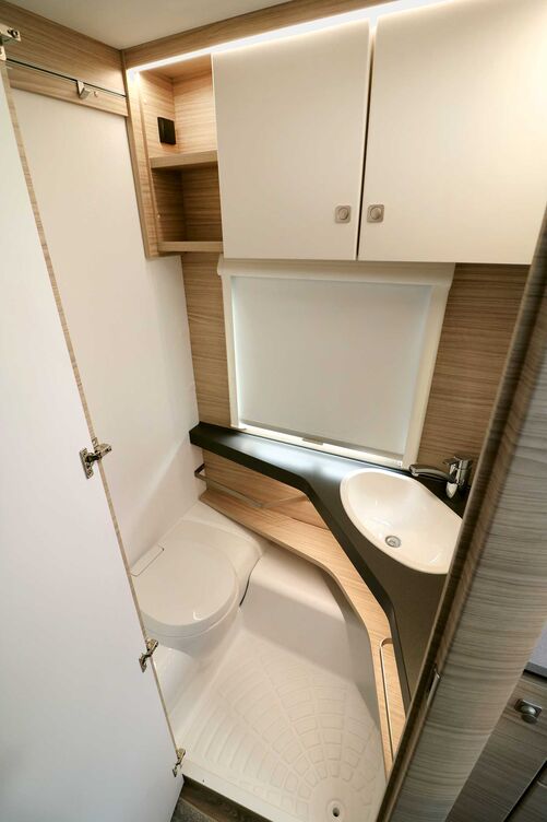 La salle de bains claire avec W. C. banc esthétique et lavabo placé dans l’angle offre tout l’essentiel malgré une surface compacte.