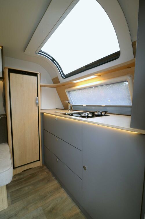 La cuisine très esthétique à l’avant, sous la grande fenêtre de toit offre beaucoup de liberté de mouvement, suffisamment de place pour travailler et beaucoup de rangements.