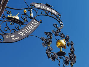 Schmiedeeiserne Wirtshausschilder, wo wie hier das Besteck schon im Braten steckt, verheissen leckere und opulente pfälzische Kochkünste.