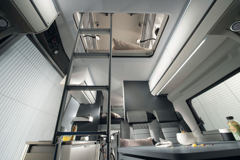 Échelle menant à l’étage, au fond le lit relevable arrière.