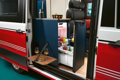 Grâce au système coulissant, le réfrigérateur est accessible de l’intérieur comme de l’extérieur. Une tablette rabattable est prévue sur le flanc extérieur de la cuisine.