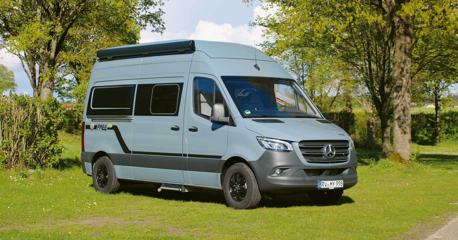 Le fourgon Sprinter Mercedes-Benz attire tous les regards avec son toit relevable parfaitement intégré, sa couleur extérieure bleu-gris et ses applications de design affirmées.