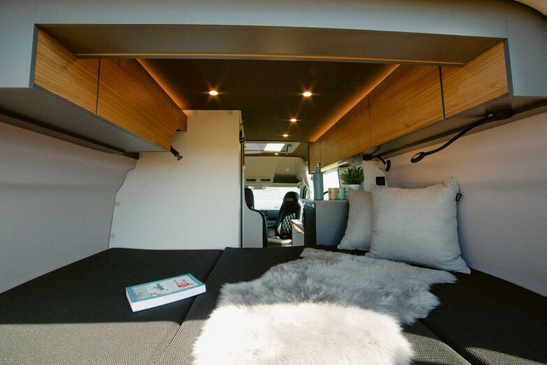 Espace nuit à l’arrière du fourgon avec de grandes armoires suspendues.