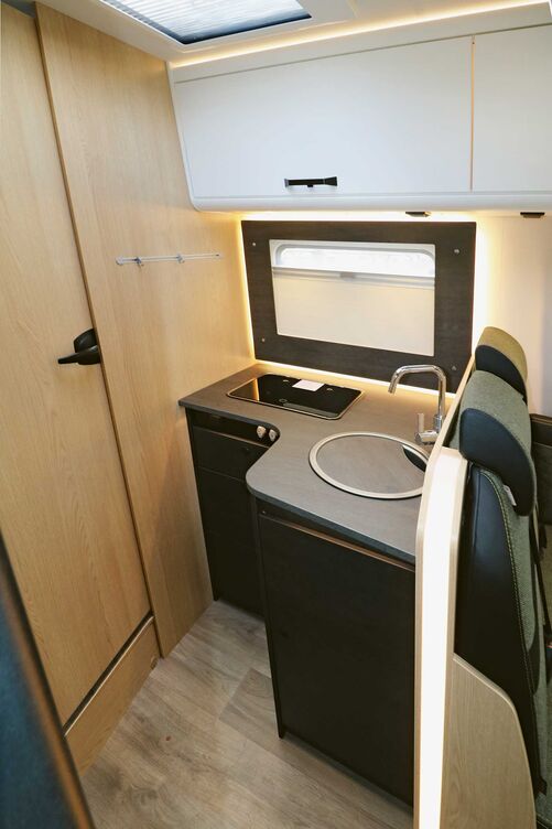 Bloc cuisine élégant avec placard bas en angle, équipement complet et nombreux éclairages.