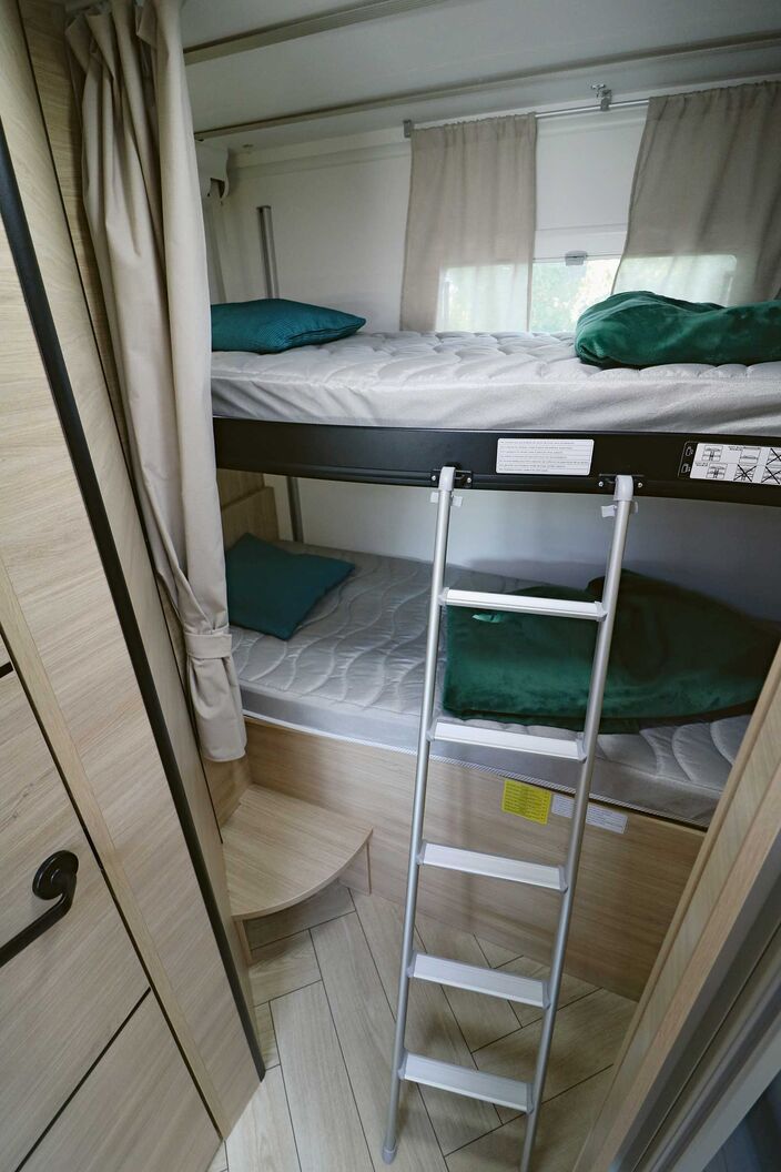 En fonction des besoins en espace, le lit superposé supérieur peut être relevé jusqu’au plafond ou abaissé jusqu’au milieu par commande électrique. Une fenêtre arrière et un rideau complètent la partie arrière.