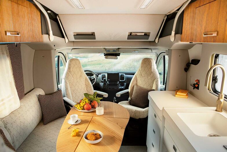 Chaleureux malgré des dimensions compactes : l’espace à vivre de l’Oasi 540.1 avec dînette en L, sièges de cabine pivotants, table coulissante et bloc-cuisine.
